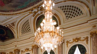 A photo of a chandelier in Asahi no Ma. The ceiling hangs suspended, made primarily of large pieces of crystal.