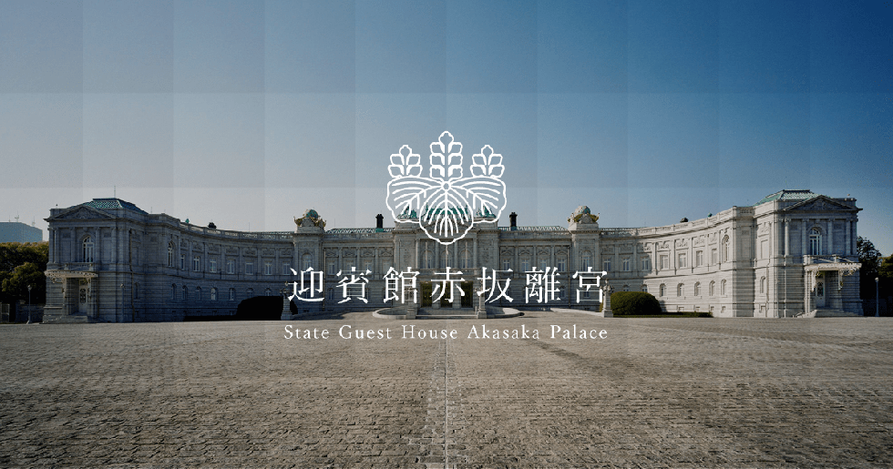 A photo of the State Guest House, Akasaka Palace, as seen from the forecourt. The symmetrical neo-Baroque style building is seen together with the broad forecourt against a background of blue skies.