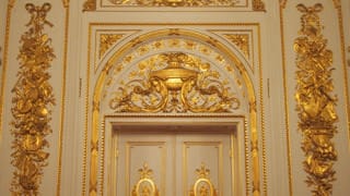 The walls near the doors are decorated with gilded stucco reliefs. A pattern of violins and other Western instruments is combined with traditional Japanese instruments, like the lute (biwa) and hand drum (tsuzumi).