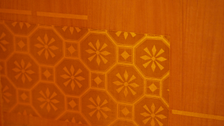 Fotografía de un panel de madera decorado con complejos incrustados de oro que forman patrones geométricos.