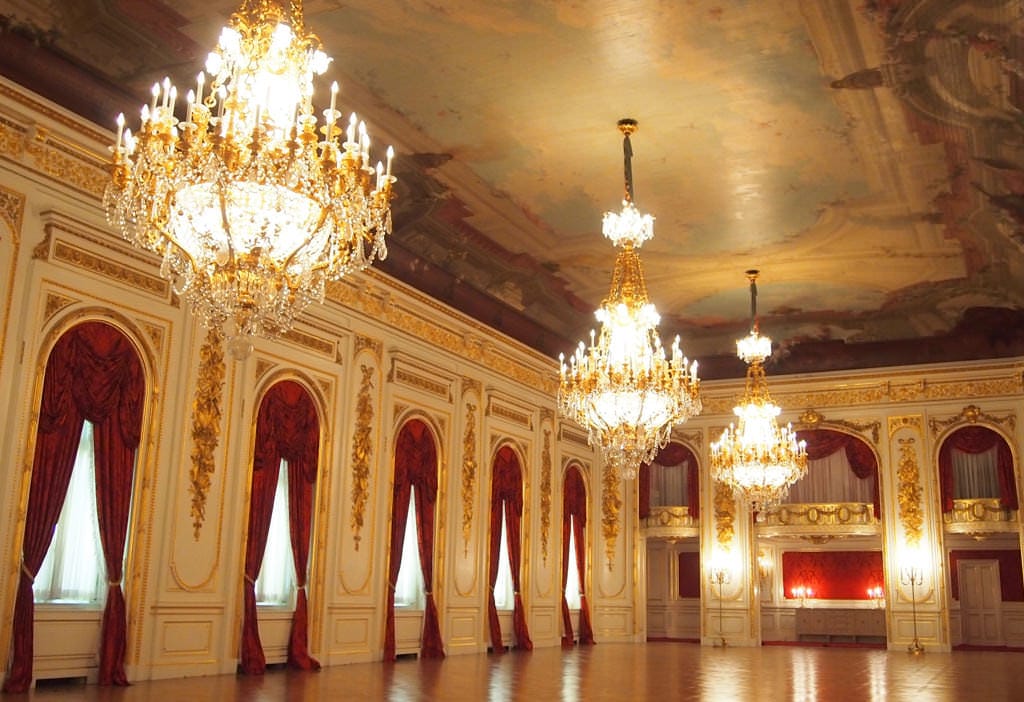 A photo of all of Hagoromo no Ma. Three chandeliers hang from the ceiling, and the parquetry flooring shines with reflected light.