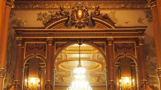 Une photo du buffet de la salle Kacho no Ma. Sur le buffet en bois sculpté se trouve un grand miroir et, vers le haut, on aperçoit l’emblème du chrysanthème impérial.
