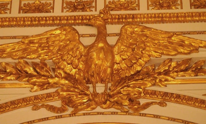 A photo of the mythical bird known as the Ran, a variety of phoenix, spreading its wings wide. It shines golden, a gilded stucco relief.