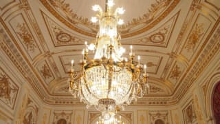 A photo of a chandelier in Sairan no Ma. A chandelier made primarily of crystal hangs from the ceiling.