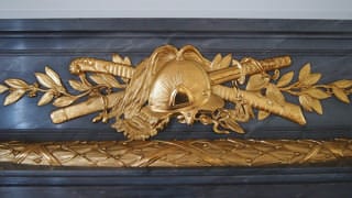 A photo of decoration on the mantlepiece in Sairan no Ma. The decoration is a design of a Western-style helmet with a Japanese katana sword and a saber behind it.