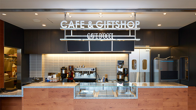 A photo of the café counter. A sign reads ’Café & Giftshop: Cave D’Occi.’
