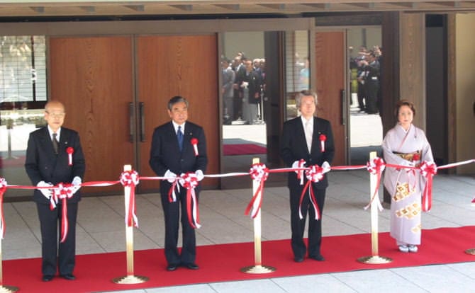 Una imagen del corte de cinta en la Ceremonia Inaugural de la Casa de Invitados del Estado en Kioto. Posando delante de la entrada, de izquierda a derecha, el Presidente del Tribunal Supremo, el Sr. Machida; Presidente de la Cámara de Representantes, el Sr. Kono, y el Primer Ministro, el Sr. Koizumi; y la Presidente de la Cámara de Consejeros, la Sra. Ogi en el extremo derecho vestida en kimono. Hay una alfombra roja extendida debajo de los cuatro. Justo en el momento en el que sus tijeras están cortando la cinta.