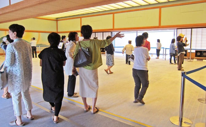 京都迎賓館開館式典におけるテープカットの様子です。正面玄関をバックに、左から町田最高裁判所長官、河野衆議院議長、小泉総理、一番右に着物を着た扇参議院議長が並んでいます。4人の足元にはレッドカーペットが敷かれています。まさにテープにはさみが入れられようとしています。