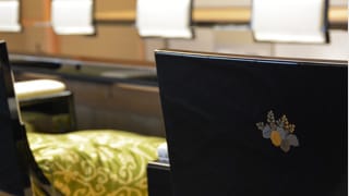 Una fotografía de cerca de la parte trasera de uno de los asientos. El emblema Goshichi no Kiri (Flor de paulonia 5-7, emblema del gobierno japonés) se ha realizado en lacado makie, el cual hace uso de pan de oro y pan de plata. 