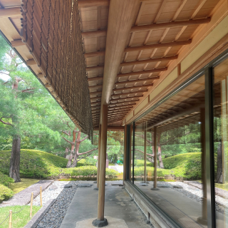 A photo of the side of a building. The building has a large glass wall, and the overhanging roof is carefully constructed with intricate woodworking.