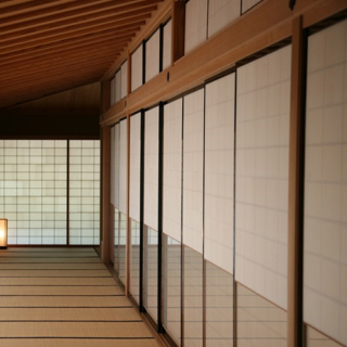 A photo of a hallway with tatami floors, Japanese sliding doors on the right, and sliding doors with shoji (rice paper) on the left.