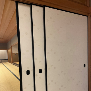 A photo of three free-standing sliding doors, each covered with white karakami paper with the State Guest House's paulownia seal.
