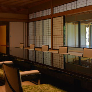 A photo of a traditional, Japanese-style room with a large, dark, glossy table in the center.