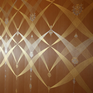 木製のパネルの表面にはめ込まれた銀と金の複雑な模様の写真。
