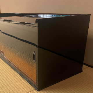 A photo of a black lacquer cabinet on the floor of a tatami room.