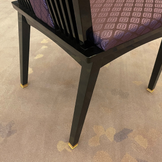 紫色の模様が入った座面クッションと、足元の金の装飾がついた黒い椅子の写真。