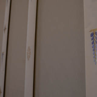 A close-up photo of a screen. Wisteria, chrysanthemums, and lotuses are embroidered onto evenly-spaced strips of cloth known as nosuji.