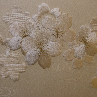 A close-up photo of white and gold flowers embroidered onto white fabric.