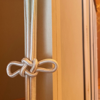 A white braided cord hangs in the center of the photo, its center tied in an intricate knot.