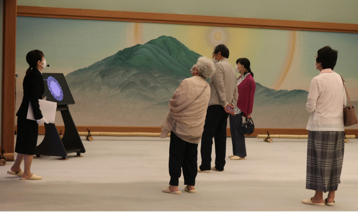 Une vue d'une visite guidée de la Maison des hôtes d'État de Kyoto. Les visiteurs admirent chaque salle de la Maison des hôtes d'État tout en écoutant les explications du guide touristique.