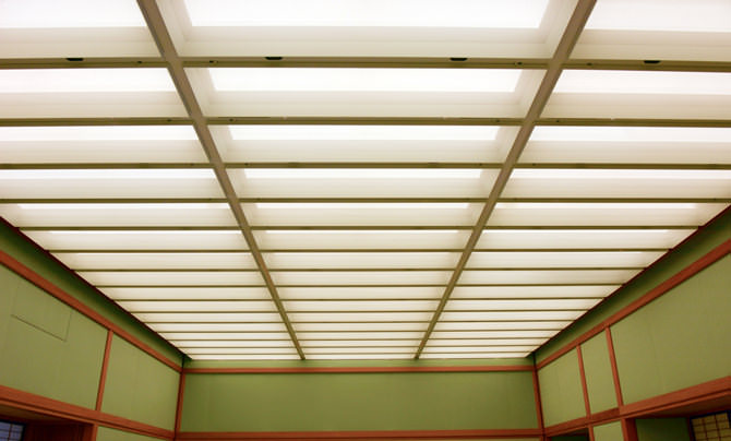 A photo of the ceiling in Yubae no Ma. The lighting is indirect, and gives off a soft light. The ceiling is divided into rectangular grids.