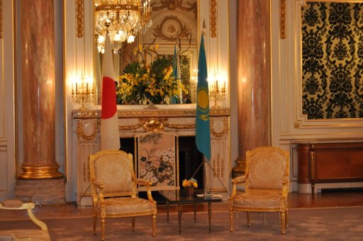 朝日の間において行われる会談会場の写真。中央には馬蹄式に並べられた金色の椅子が、その後ろにはカザフスタン共和国と日本の国旗が並べられています。