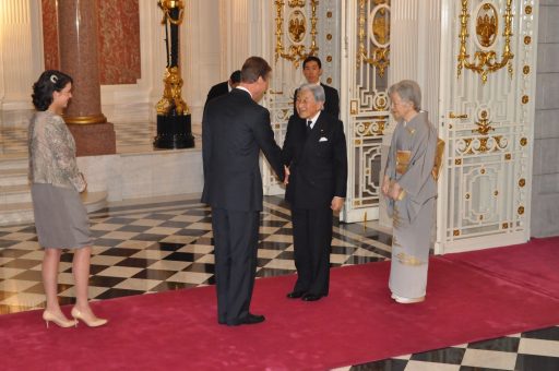 迎賓館赤坂離宮の本館玄関ホールにおいて、ルクセンブルク大公国アンリ大公殿下とアレクサンドラ王女殿下が天皇皇后両陛下をお出迎えしている写真。大公殿下と天皇陛下が握手をしています。