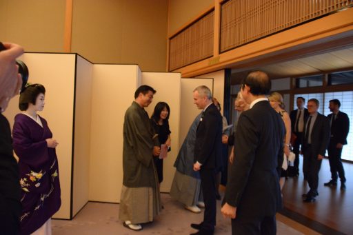 藤の間の入り口の屏風の前で、国民議会議長一行が一列に並んだ京都市長、京都市会議長や芸妓さんから挨拶を受ける様子の写真