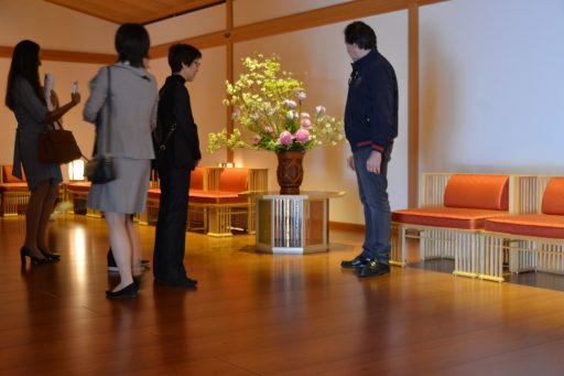 Members of the delegation are appreciating ikebana flower arrangement in Juraku no Ma room while visiting the facility.